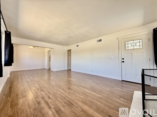 A spacious room with wooden flooring and white walls.