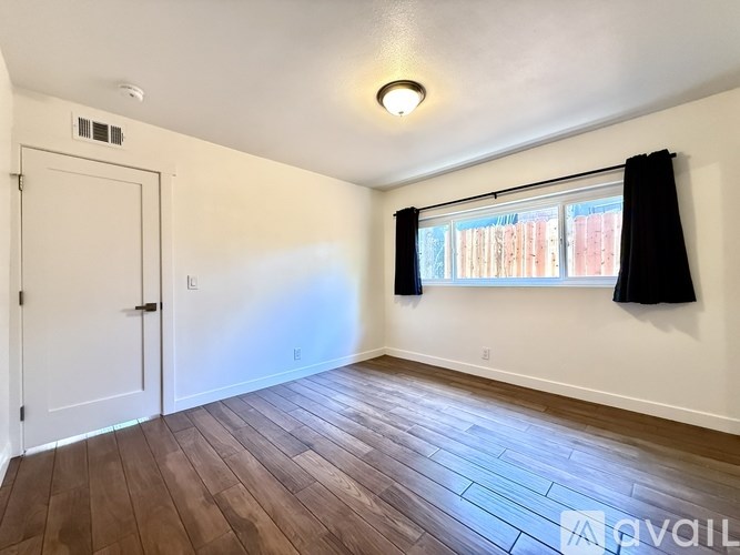 A room with a white door and a window with black curtains.