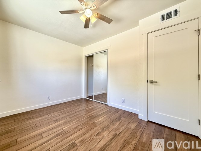 A room with a ceiling fan and wooden flooring.