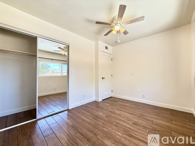 A room with a ceiling fan and wooden flooring.