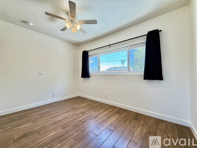 A room with a ceiling fan and a window with black curtains.