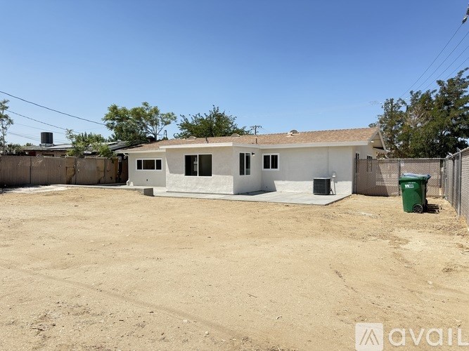 A white house with a green trash can in front of it.