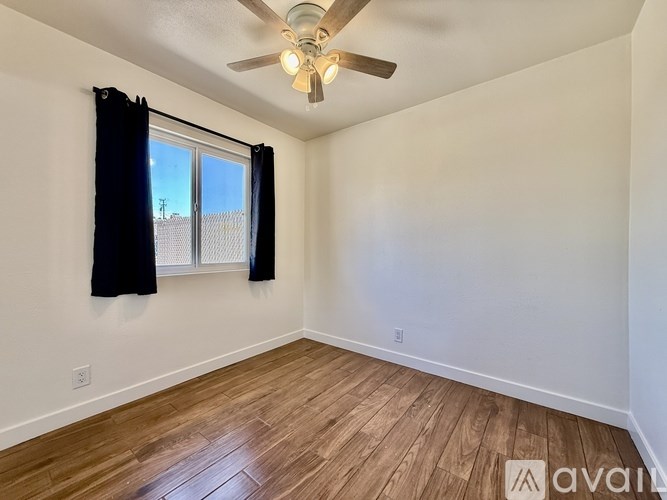 A room with a ceiling fan and wooden flooring.