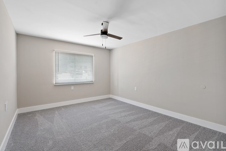 A room with a ceiling fan and a window with blinds.