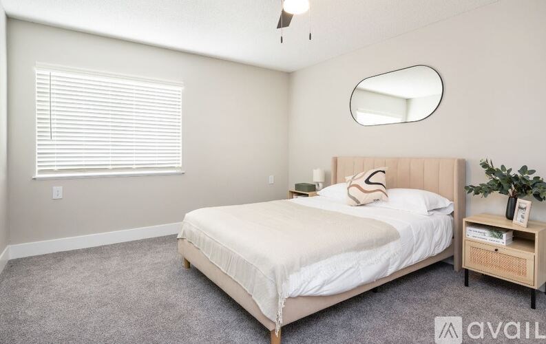 A bedroom with a bed, nightstand, and a round mirror on the wall.