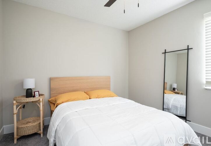 A bedroom with a bed, nightstand, and mirror.