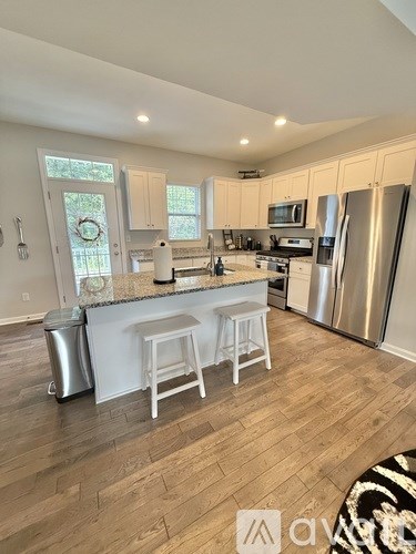 A kitchen with white cabinets and a wooden floor.