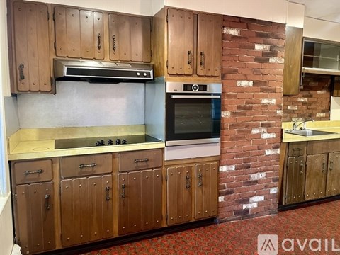 A kitchen with wooden cabinets and a brick wall.