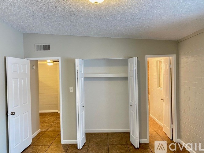 A white door is open to a room with a white wall and a white fridge.