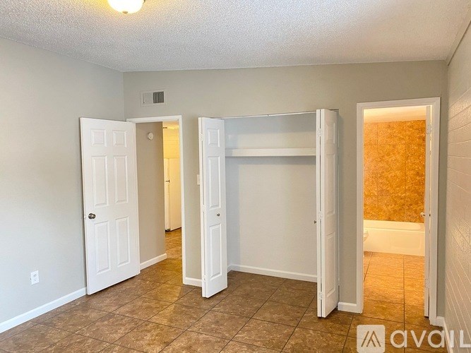A room with white walls and a tiled floor with a doorway leading to another room.