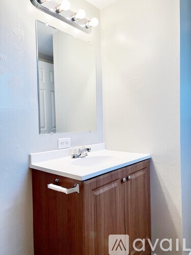 A bathroom with a white counter and a brown cabinet.