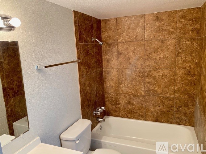 A bathroom with brown tiles and a white toilet.
