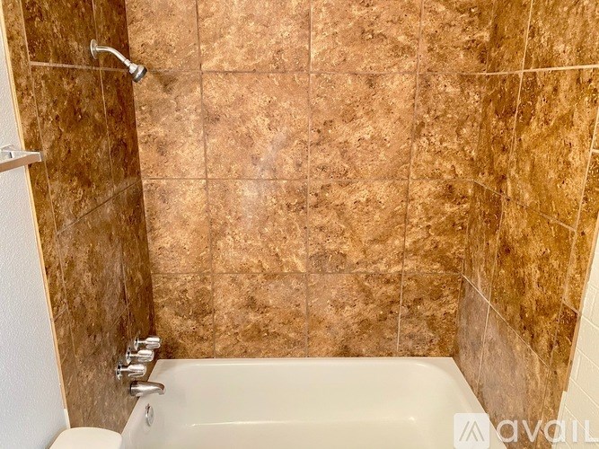 A bathroom with a tiled wall and a white bathtub.