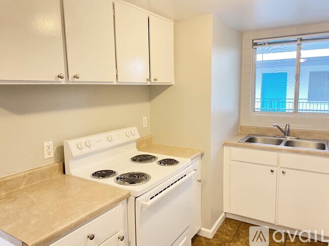 A kitchen with white cabinets and a white stove top oven.