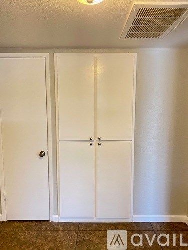 Two white doors in a room with a tiled floor.