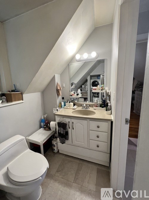 A bathroom with a toilet, sink, and mirror.