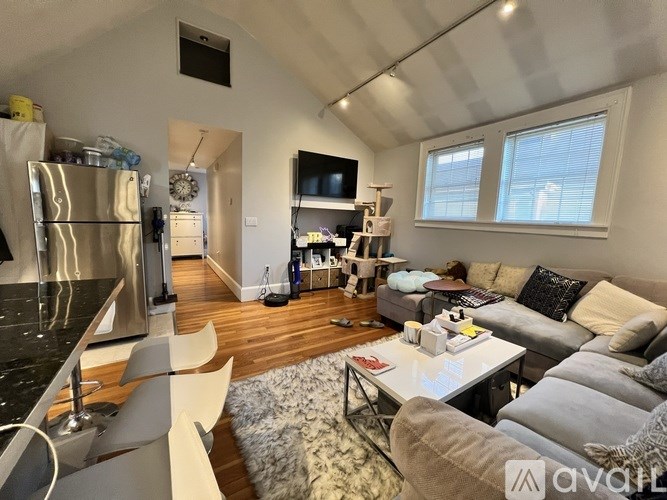 A modern living room with a kitchen area in the background.