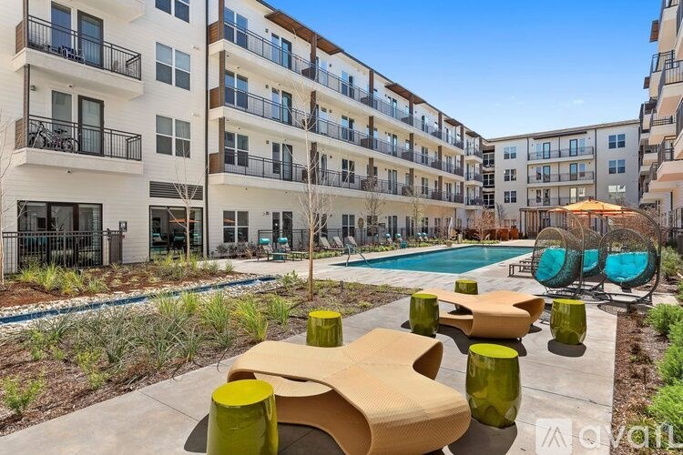 A modern apartment complex with a pool and outdoor seating area.