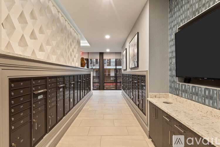 A hallway with a row of mailboxes on the left and a wall with a diamond pattern on the other side.