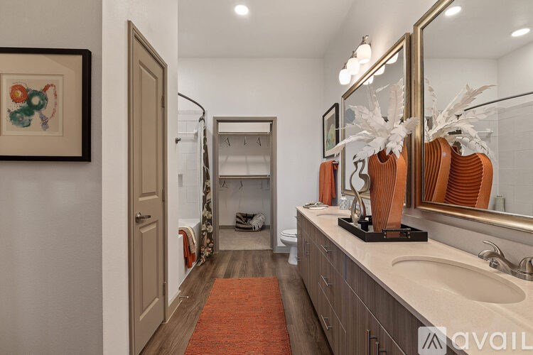 A bathroom with a large mirror and a red rug.