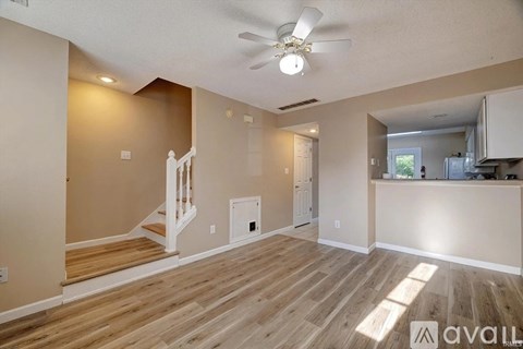 A living room with a staircase and a kitchen area in the background.