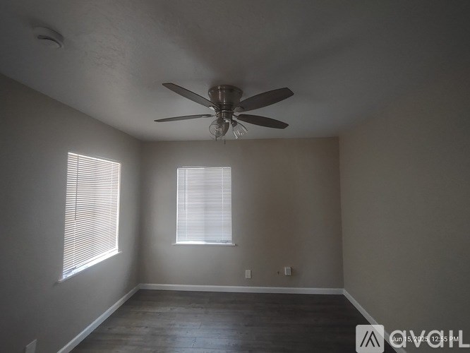 A room with a ceiling fan and a window with blinds.