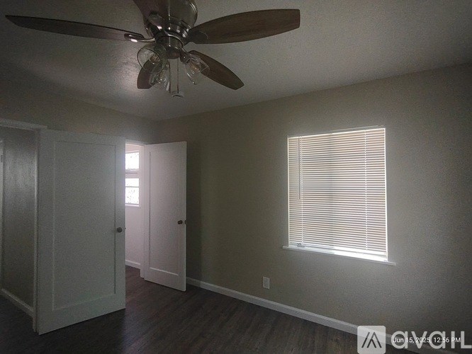 A room with a ceiling fan and a window with blinds.