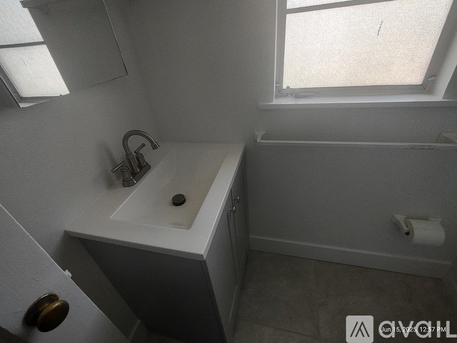 A white sink in a small bathroom with a window above it.