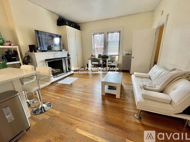 A living room with a fireplace and a television on the wall.