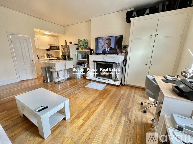 A living room with a white coffee table and a television on the wall.