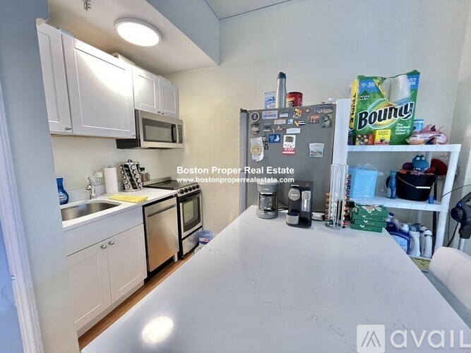 A kitchen with white cabinets and a refrigerator with magnets on it.