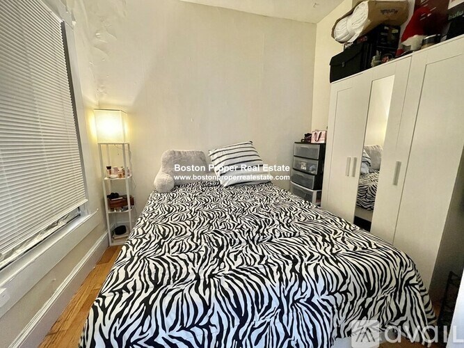 A bedroom with a zebra print bedspread and a white wardrobe.