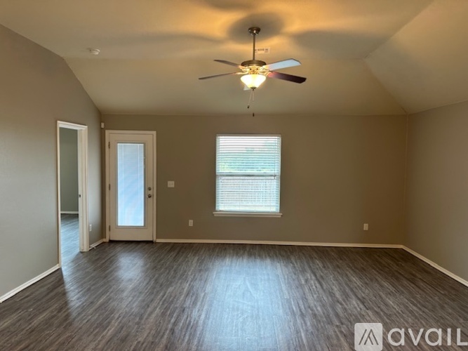 A spacious room with a ceiling fan and two windows.