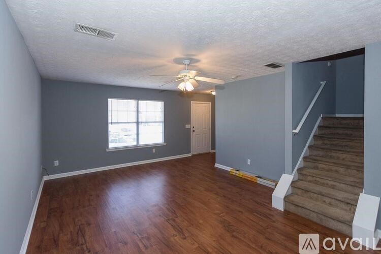 A room with wooden floors and a staircase leading to another room.