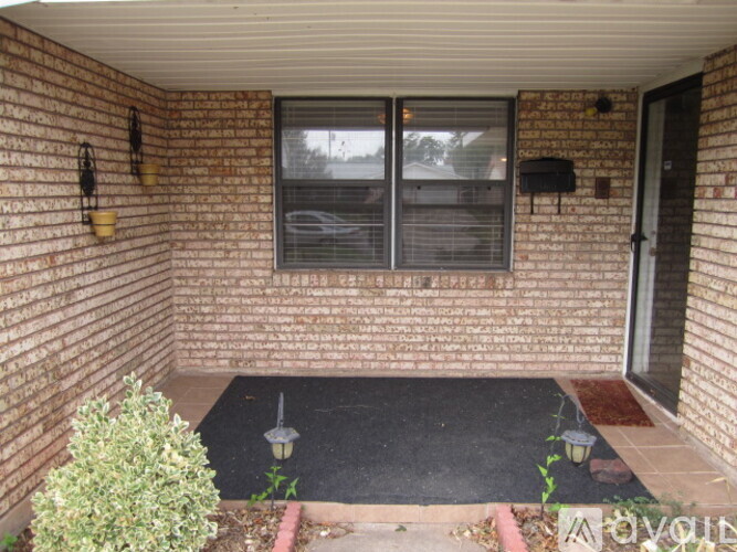 A small patio with a black mat and a small bush.