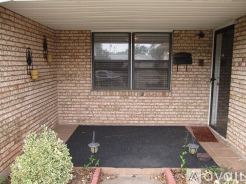 A small patio with a black mat and a small bush.
