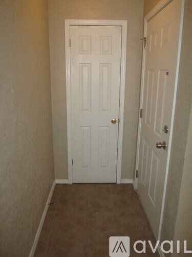 A white door is in a room with carpeted flooring.