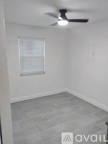 A room with a ceiling fan and a window with blinds.
