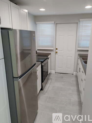 A kitchen with a stainless steel refrigerator and white cabinets.