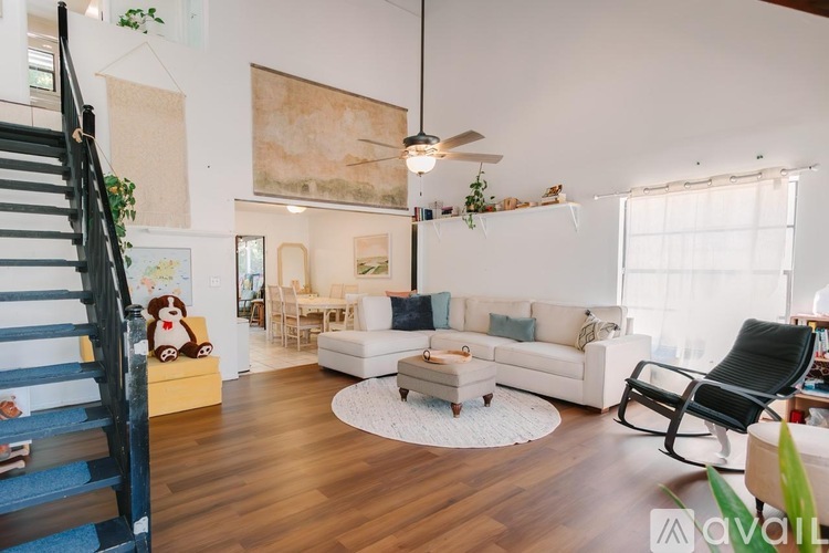 A living room with a white couch, a coffee table, and a staircase.