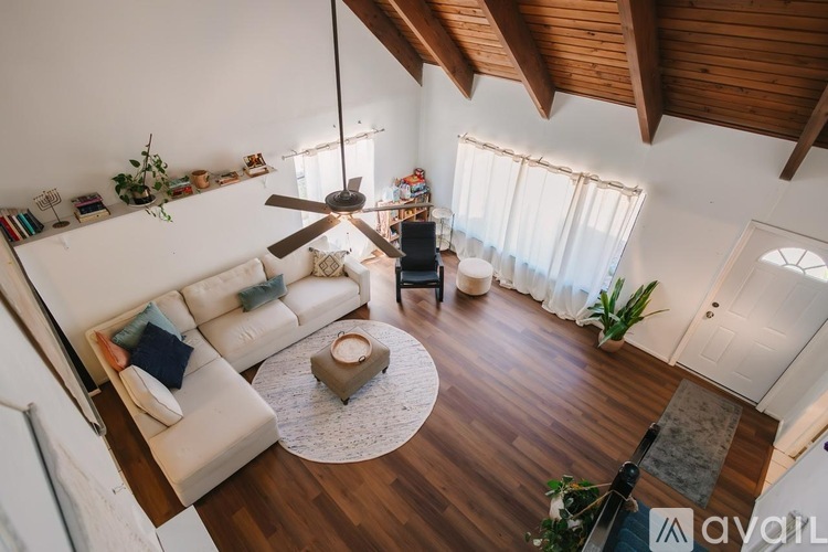 A living room with a white couch and a rug in the middle.