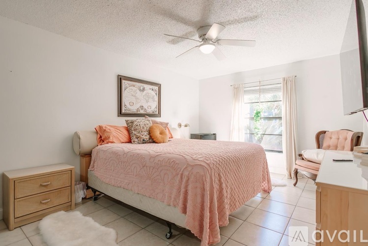 A bedroom with a bed, chair, and a ceiling fan.