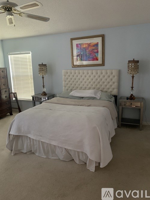 A bedroom with a large bed and a ceiling fan.