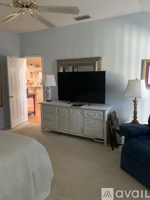 A living room with a television, a bed, and a dresser.