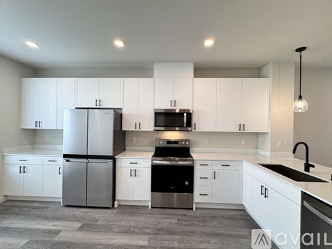 A modern kitchen with white cabinets and stainless steel appliances.