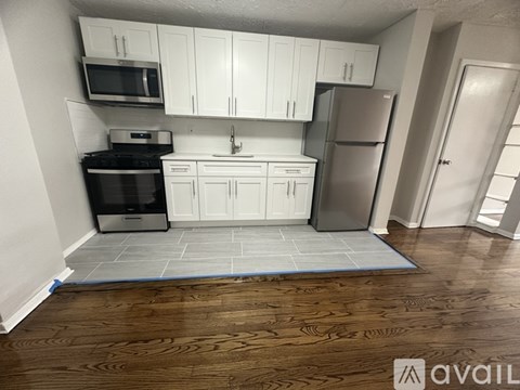 A kitchen with white cabinets and a refrigerator.