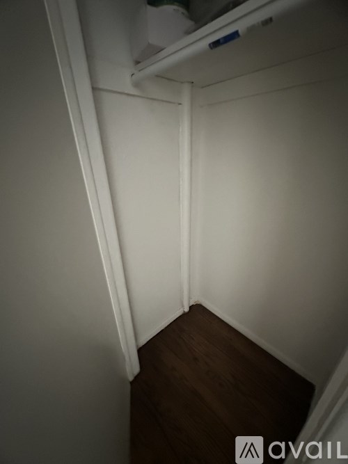 A small, dark room with a white door and a white wall.