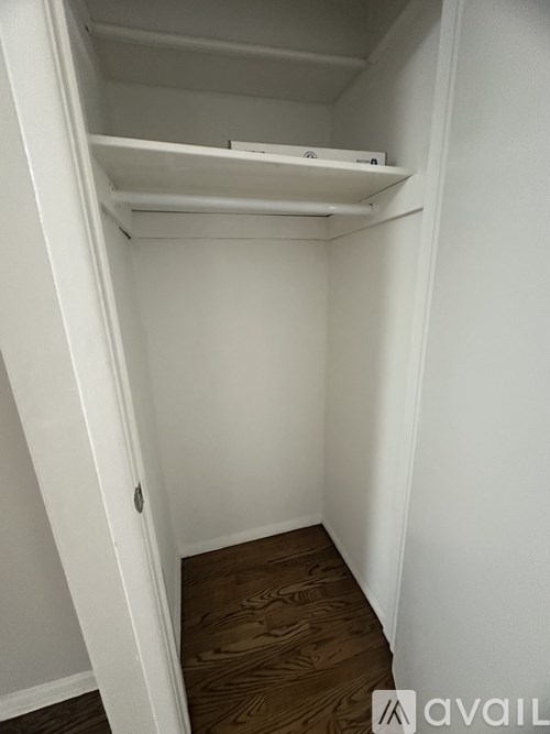 A small white closet with a shelf and a door.