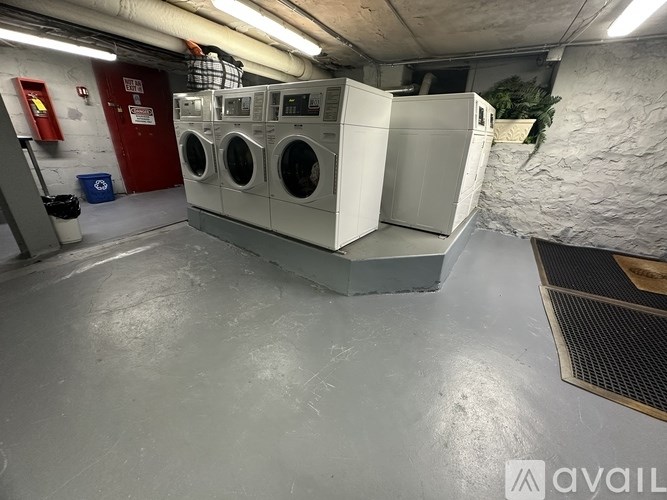 A laundry room with washing machines and a red door.