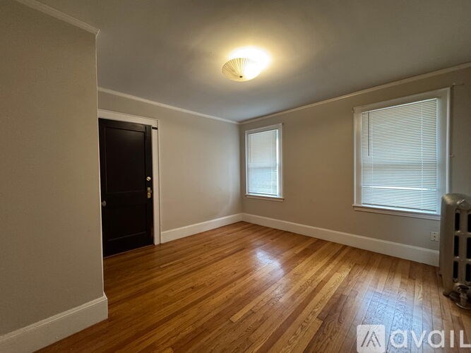 A room with wooden floors and a window with blinds.